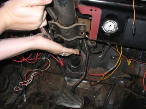1978 Ford Bronco - Hands work on the steering column and exposed wiring inside a 1978 Ford Bronco.