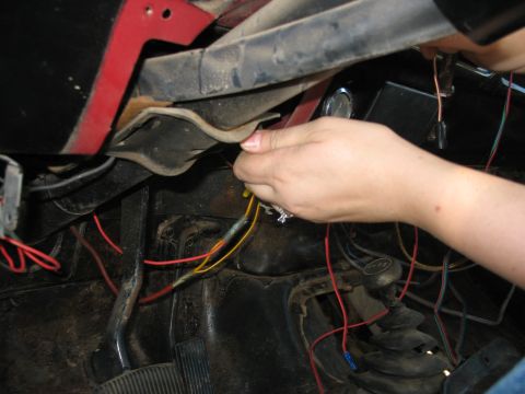 1978 Ford Bronco - A person is working on the wiring harness under the dashboard of a vehicle.