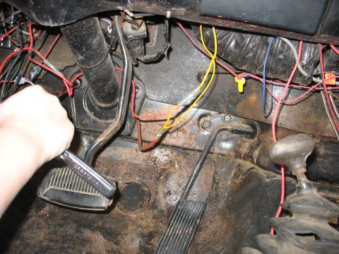 1978 Ford Bronco - Close-up of vehicle interior showing brake and gas pedals, exposed wiring, and a hand working on the brake pedal.