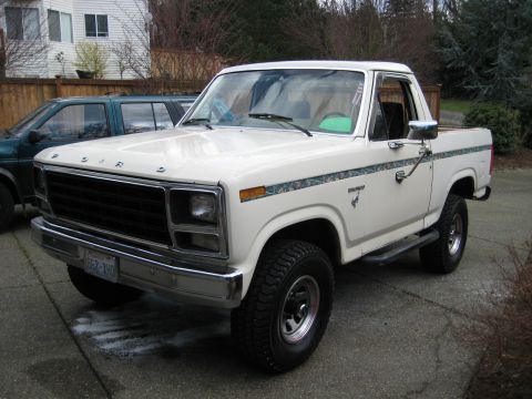 1980 Ford Bronco - A white Ford Bronco is parked in a driveway with a house and trees in the background.