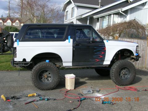 1996 Ford Bronco - A lifted Ford Bronco is parked outside a house with tools and equipment scattered around it.