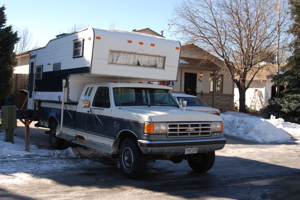 1987 Ford F-250 with a camper shell parked in a snowy driveway