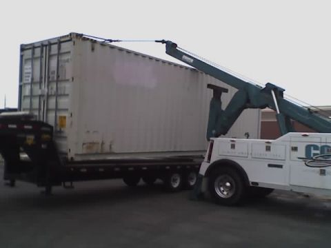 1992 Ford Bronco - A tow truck is actively lifting a large shipping container from a trailer.