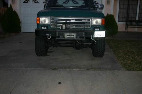 1991 Ford Bronco - This green Ford Bronco features a winch and 'BAJA' decals, suggesting off-road modifications.