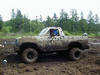 Mud-covered light-colored Ford 4x4 truck parked in a muddy field after off-roading