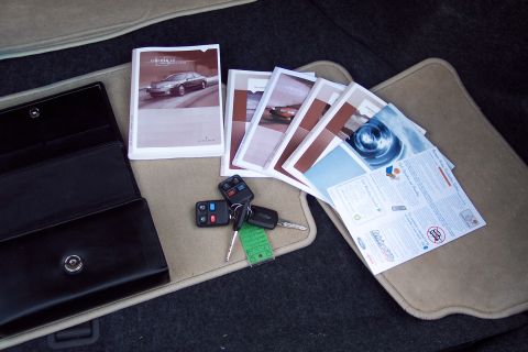 2001 Ford Crown Victoria - Car owner's manual, keys, and a black leather case are laid out on the floor mats inside a vehicle.