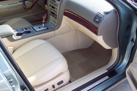 2001 Ford Crown Victoria - The interior of a car shows beige leather seats and a wood-trimmed dashboard.