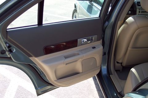 2001 Ford Crown Victoria - The interior door panel of a Lincoln LS features wood trim and beige upholstery, with another vehicle visible through the window.