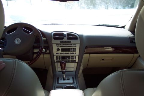 2001 Ford Crown Victoria - The interior of a 2006 Lincoln LS features a wood-trimmed dashboard and a beige leather interior.