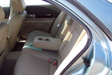 2001 Ford Crown Victoria - The interior view shows the rear seats of a car, beige leather upholstery and a center armrest with cup holders.