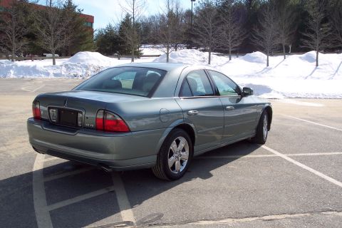 2001 Ford Crown Victoria - A teal Lincoln LS is parked in a lot with snow-covered hills and trees in the background.