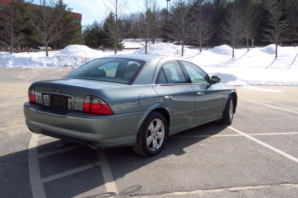 Rear 3/4 view of a teal Lincoln LS parked in a lot with snow in the background