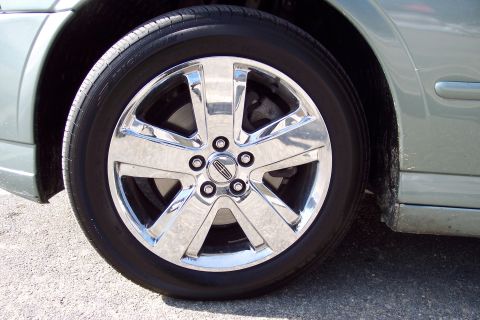 2001 Ford Crown Victoria - Close-up of a chrome wheel the Lincoln logo, attached to a light green car.