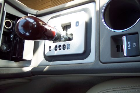 2001 Ford Crown Victoria - The interior of a car displays a gear shifter and an electronic parking brake button.
