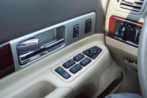 2001 Ford Crown Victoria - Close-up of a car's interior door panel, showing the chrome door handle, power window controls, and wood accents.