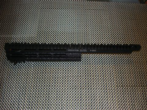 2005 Nissan Titan - A close-up view of a black firearm accessory rail, identified by markings, resting on a patterned background.