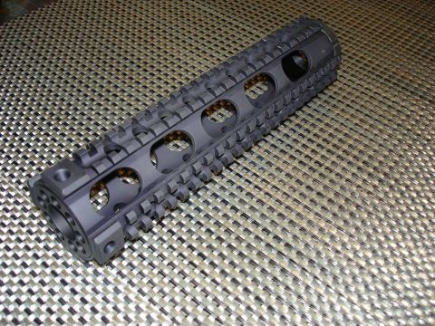 2005 Nissan Titan - A black AR-15 handguard with tactical rails is shown from an angled perspective on a patterned background.
