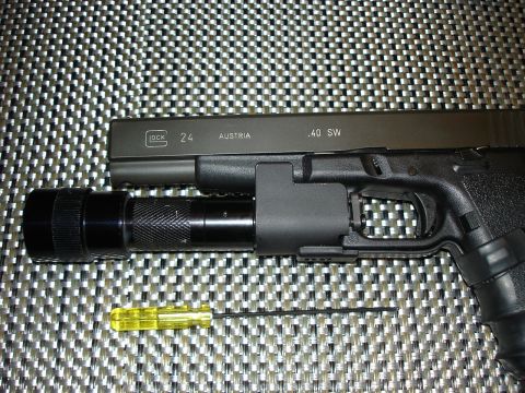 2005 Nissan Titan - A Glock pistol is shown with a mounted flashlight and a small tool on a textured surface.