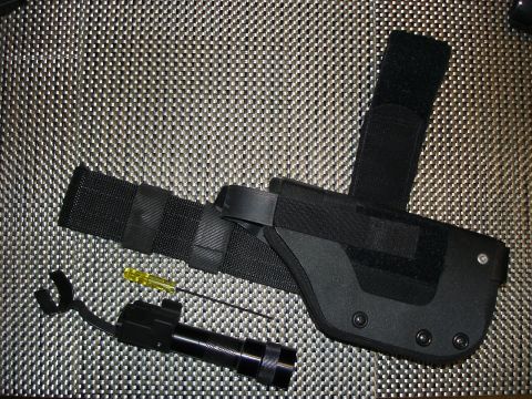 2005 Nissan Titan - A tactical thigh holster, flashlight, and screwdriver are laid out on a textured background.