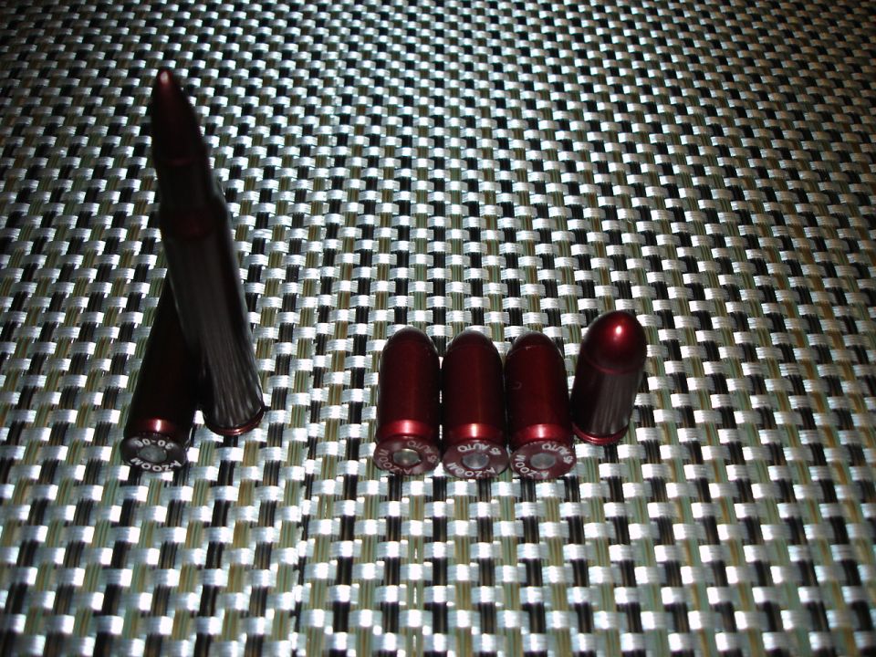Red A-Zoom snap cap dummy cartridges in .30-06 and .45 Auto on a woven placemat