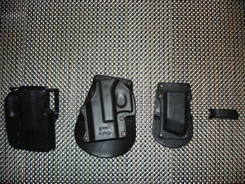 Black polymer pistol holsters and magazine pouch arranged on a woven mat, not a vehicle photo
