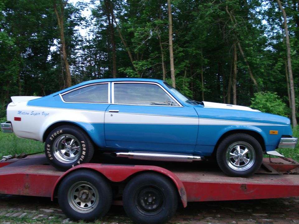 Blue and white Vega hatchback with Super Stock wheels on a red trailer