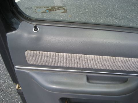 1981 Ford Bronco - Close-up of a vehicle's interior door panel, showing gray plastic and fabric trim details.