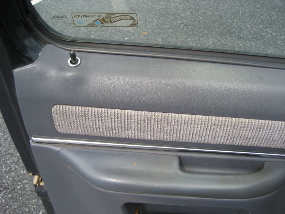 Gray car door panel with fabric insert and chrome trim