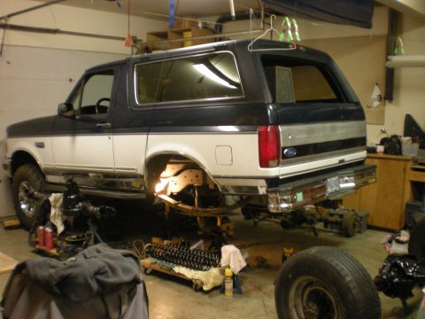 1993 Ford Bronco - This two-tone Ford Bronco is undergoing a suspension overhaul in a garage setting.