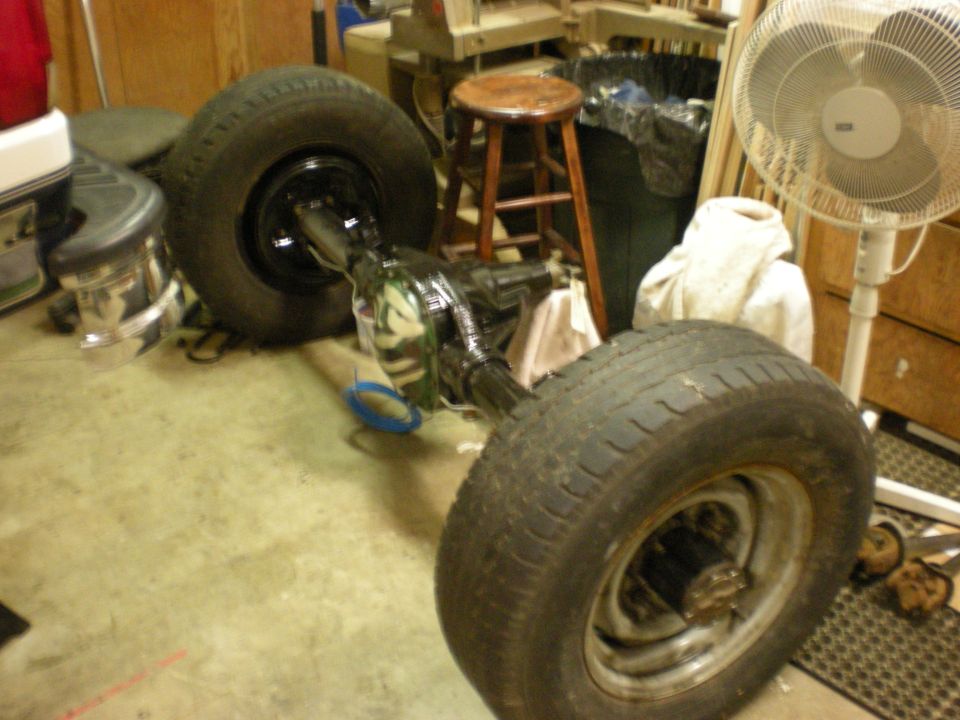 Rear axle assembly with two tires, one on each side, in a garage setting