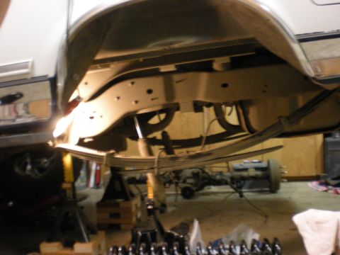1993 Ford Bronco - Close-up view of the undercarriage of a white vehicle, focusing on the suspension and leaf spring system.