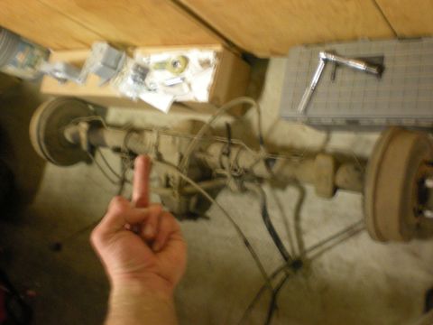1993 Ford Bronco - Rear axle assembly with brake drum and a hand giving the middle finger.