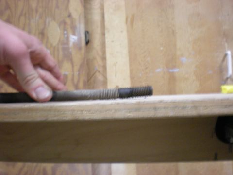 1993 Ford Bronco - A metal rod with threaded ends is examined against a wooden background.