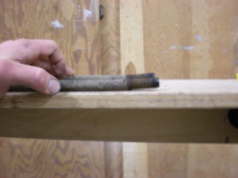 1993 Ford Bronco - A close-up view of a tie rod end, held by a hand against a wooden background.