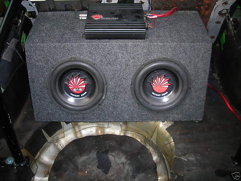 Car audio amplifier and dual subwoofer box with red wiring. Text on speakers reads 'street boom'
