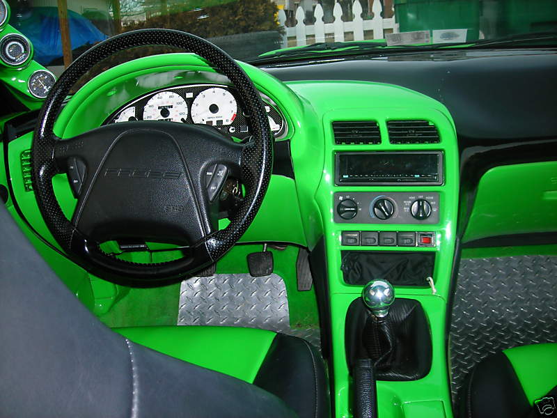 1994 Ford Probe interior with bright green dashboard, custom steering wheel, and diamond plate floor mats