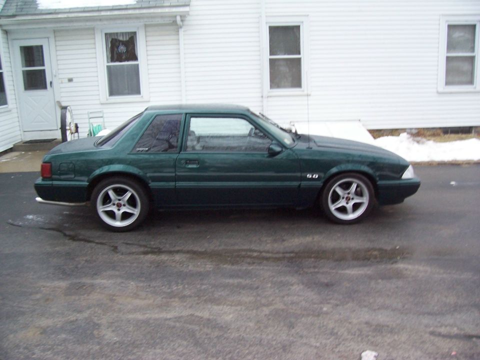 Green 1991 Ford Mustang coupe parked in front of a white house