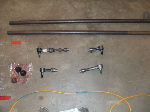 1996 Ford Bronco - Various steering linkage components, including tie rods and drag links, are arranged on a concrete surface.