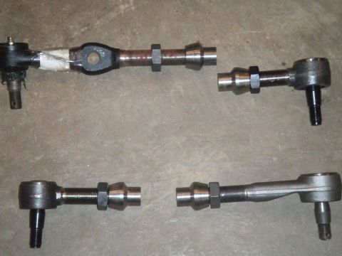1996 Ford Bronco - Several automotive steering linkage parts are displayed on a concrete surface, with a website watermark at the bottom.