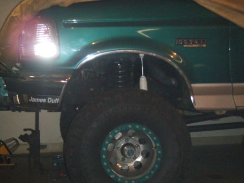 1996 Ford Bronco - A green 1996 Ford Bronco is shown with large off-road tires and custom wheels, indicating modifications.