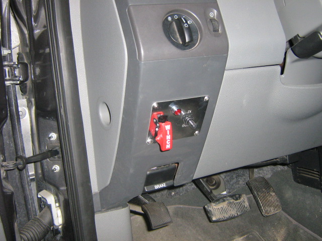 Interior shot of a vehicle's dashboard showing aftermarket switches and pedals. The word "BRAKE" is visible on a panel