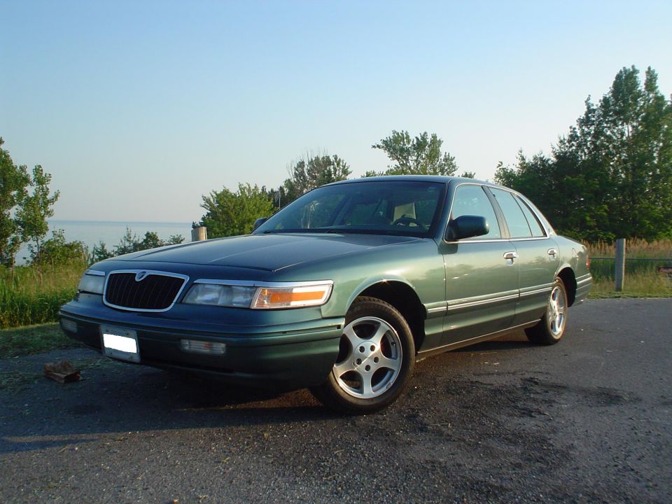 1996 Mercury Grand Marquis, green, parked on asphalt near water and trees