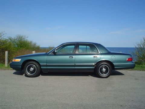 1996 Mercury Grand Marquis - A green 1996 Mercury Grand Marquis is parked on a road with the ocean in the background.
