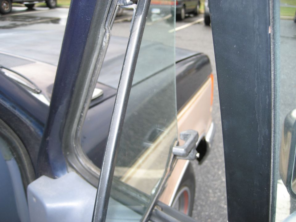 view through open driver's door of a pickup truck, showing part of another truck behind it