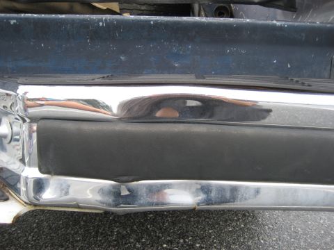 1981 Ford Bronco - Close-up of a vehicle's front bumper, revealing chrome and black rubber details.