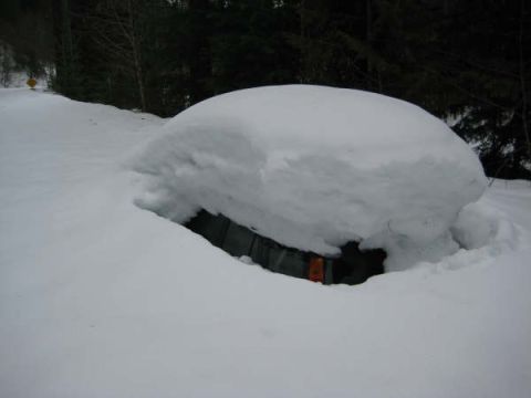 1980 Ford Bronco - A vehicle is almost completely submerged under a thick blanket of snow, with only a small portion of its front visible.