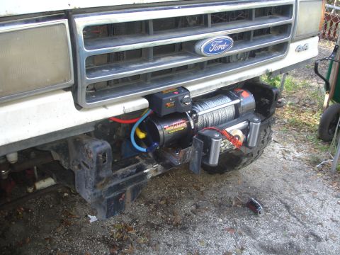 1989 Ford Bronco - Front view of a white Ford Bronco with a winch installed. The grille shows the Ford logo and 4x4 badging.