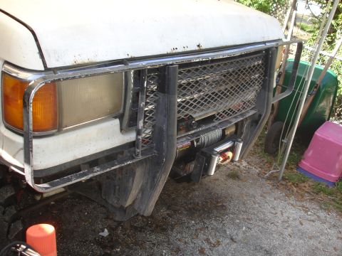1989 Ford Bronco - The front of a white truck is shown with a brush guard and a winch, suggesting it's an older model.