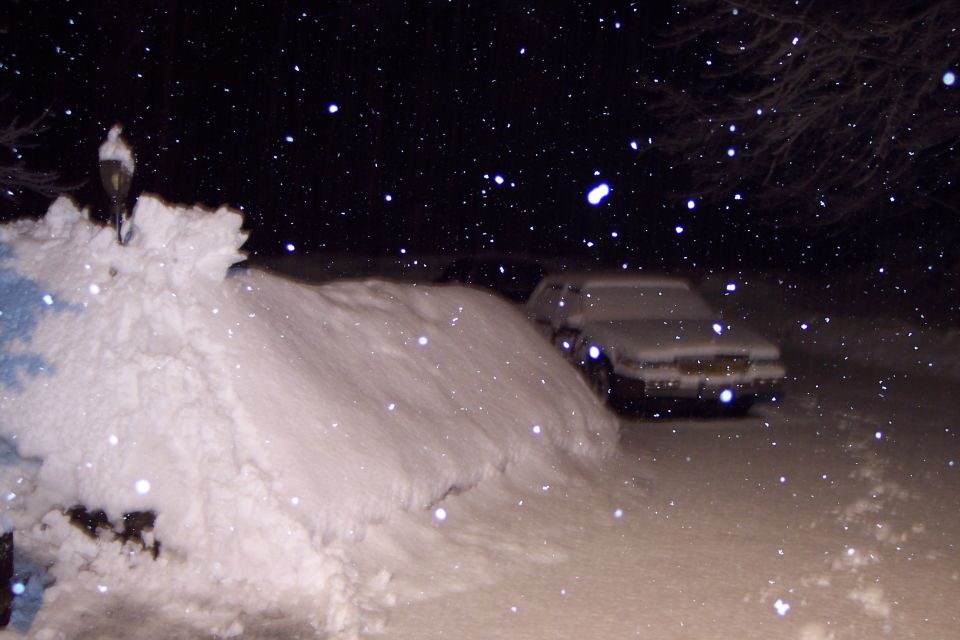 White 2001 Ford Crown Victoria covered in snow, parked on a snowy road at night