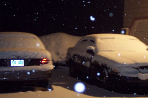 2001 Ford Crown Victoria - Two cars, including a 2001 Ford Crown Victoria, are covered in snow at night.